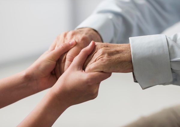 enfermera-sosteniendo-manos-hombre-mayor-simpatia